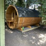 Side view of wooden barrel garden sauna 330 with balcony installed outdoors