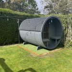 Rear exterior view of wooden barrel garden sauna in garden