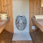 Stone heat shield behind wood-fired heater in barrel sauna 330