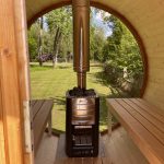 Wood-fired sauna heater inside wooden barrel sauna